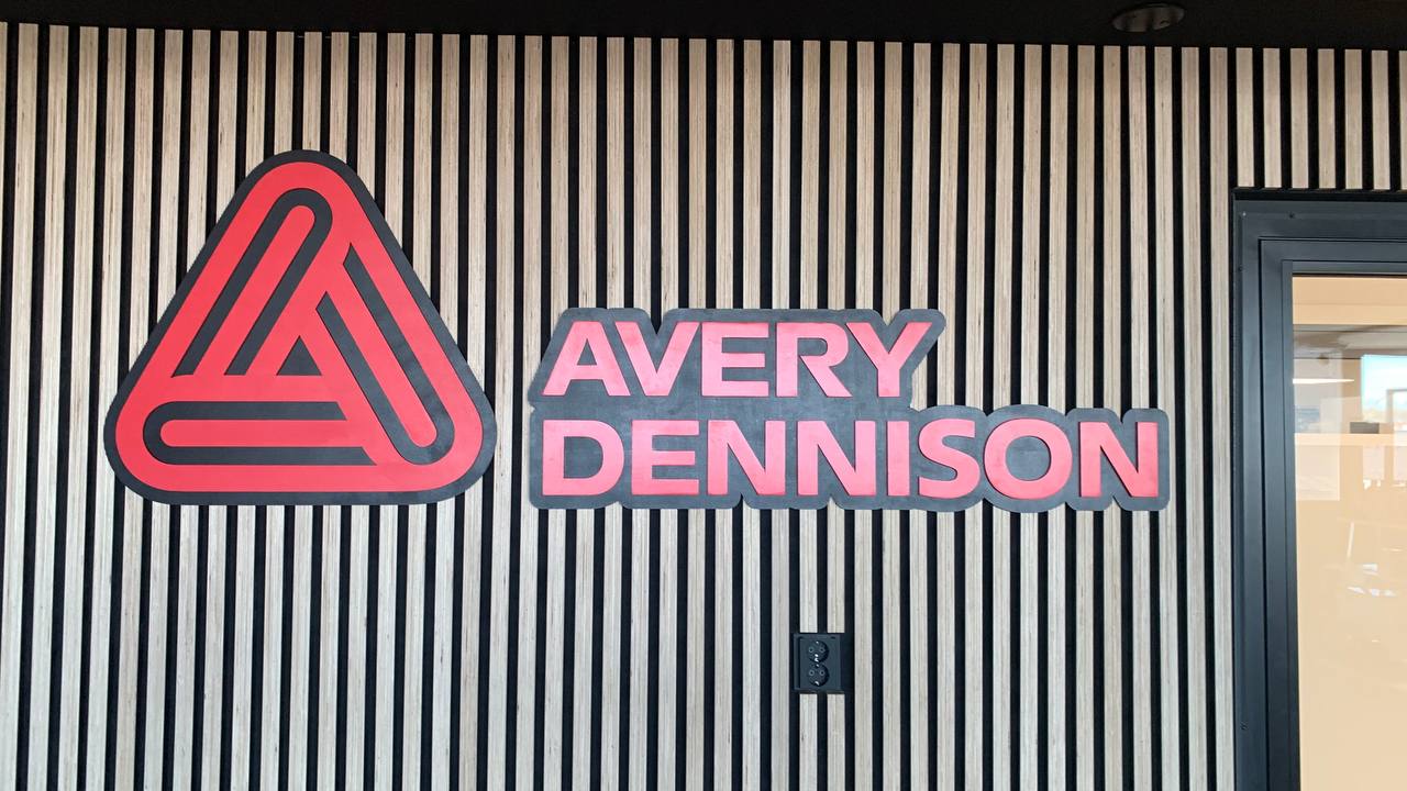 Avery Dennison – 3D-logo laserleikattuna MDF:stä 2 Avery Dennisonin yrityslogo seinäasennuksena modernissa toimistoympäristössä.