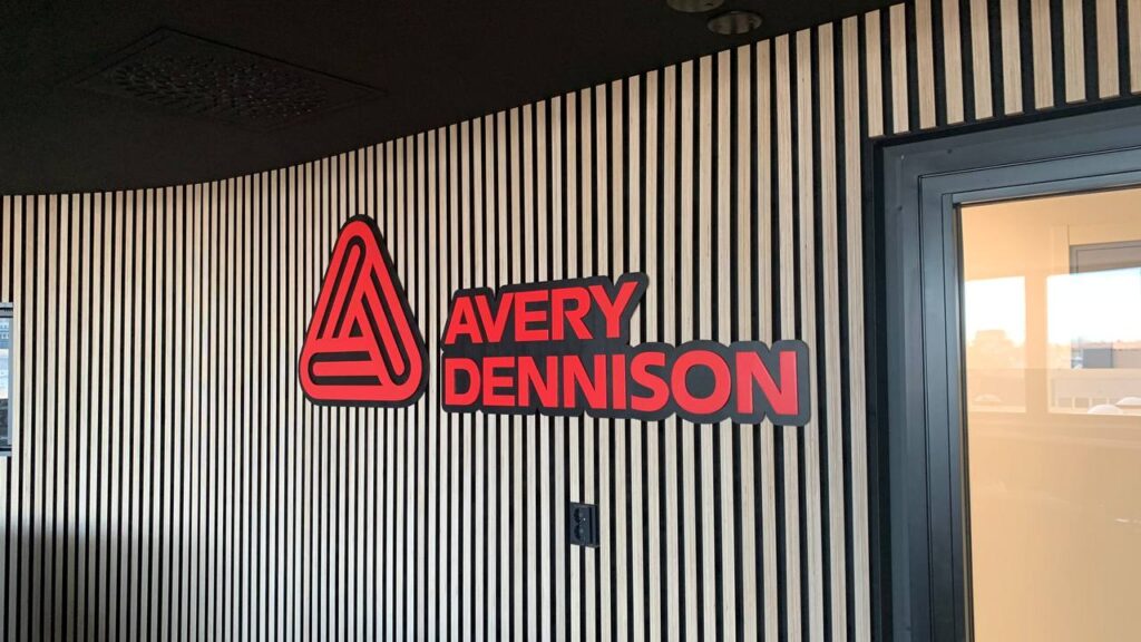 Avery Dennisonin kolmikerroksinen 3D-logo yrityksen sisätiloissa puulamelliseinällä.