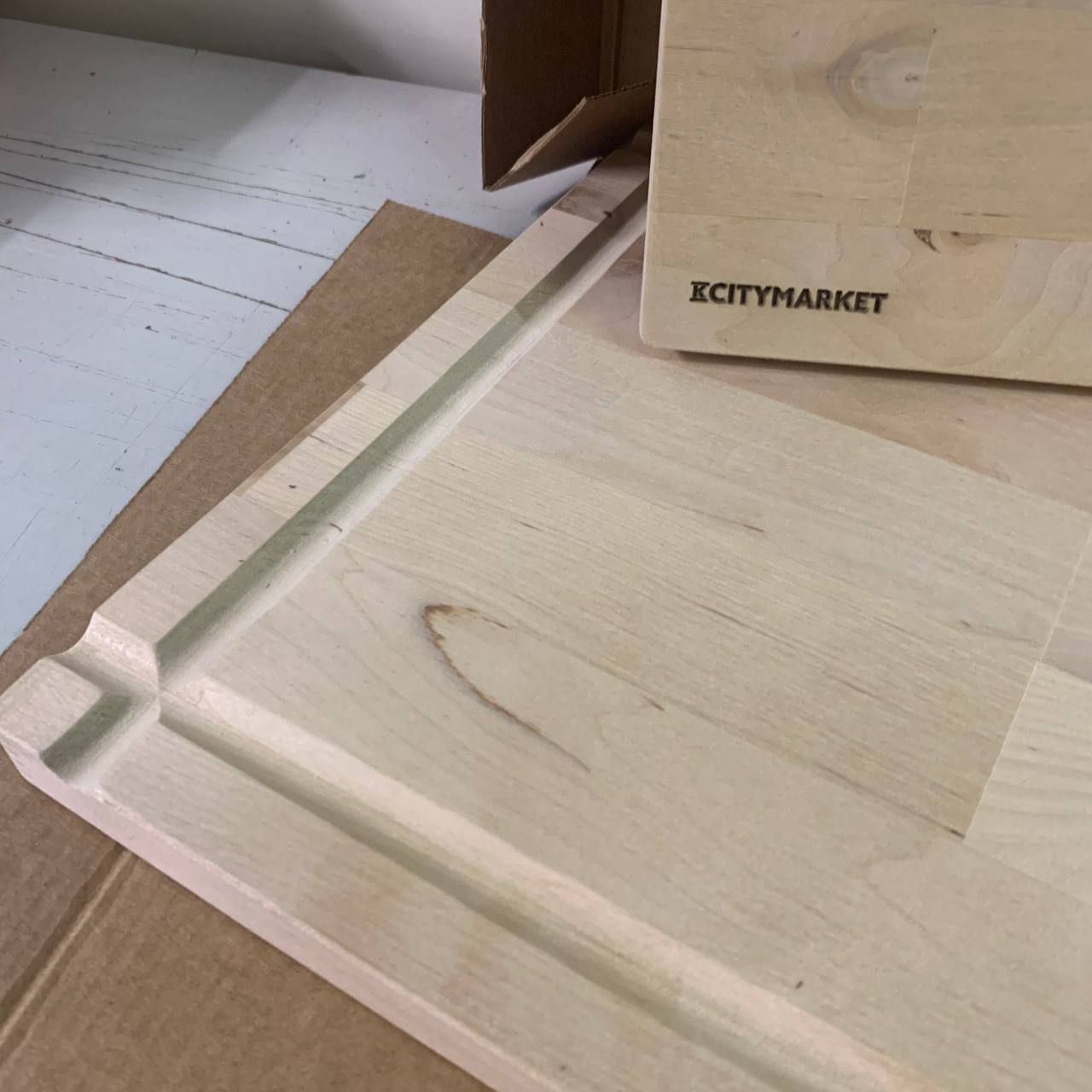 Leikkuulautojen Laserkaiverrus Lankkupojat-kumppanuudessa 1 Puinen leikkuulauta, jossa laserkaiverrettu KCITYMARKET-logo ja uritus.