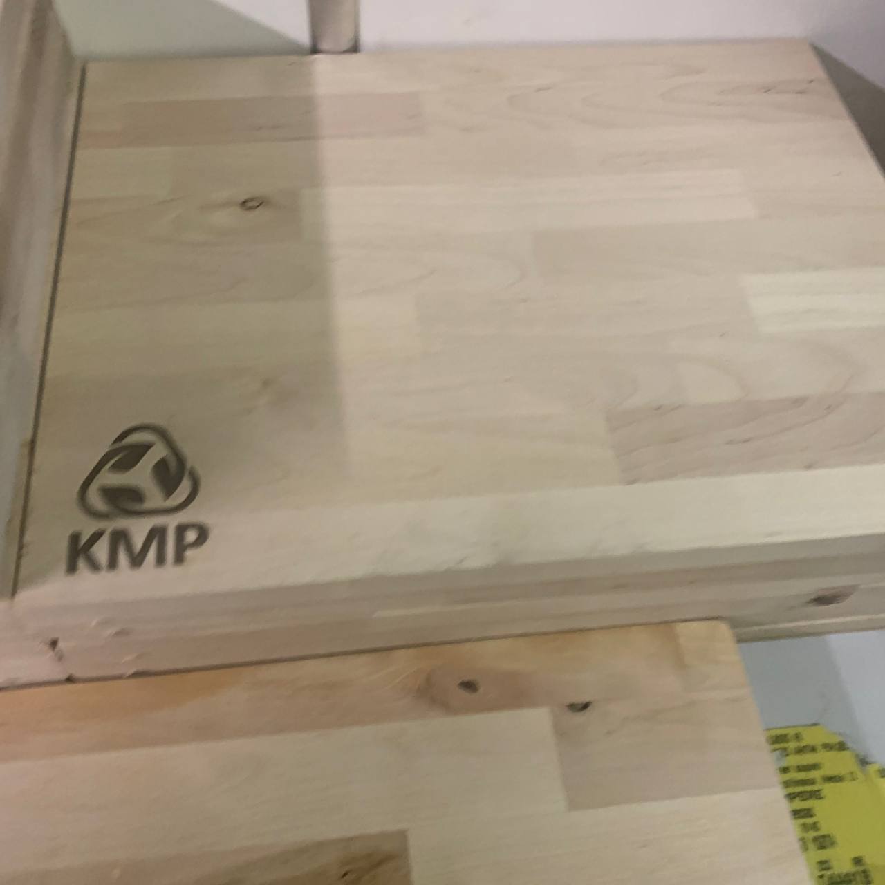 Leikkuulautojen Laserkaiverrus Lankkupojat-kumppanuudessa 6 Pino puisia leikkuulautoja, joissa laserkaiverrettu KMP-logo.