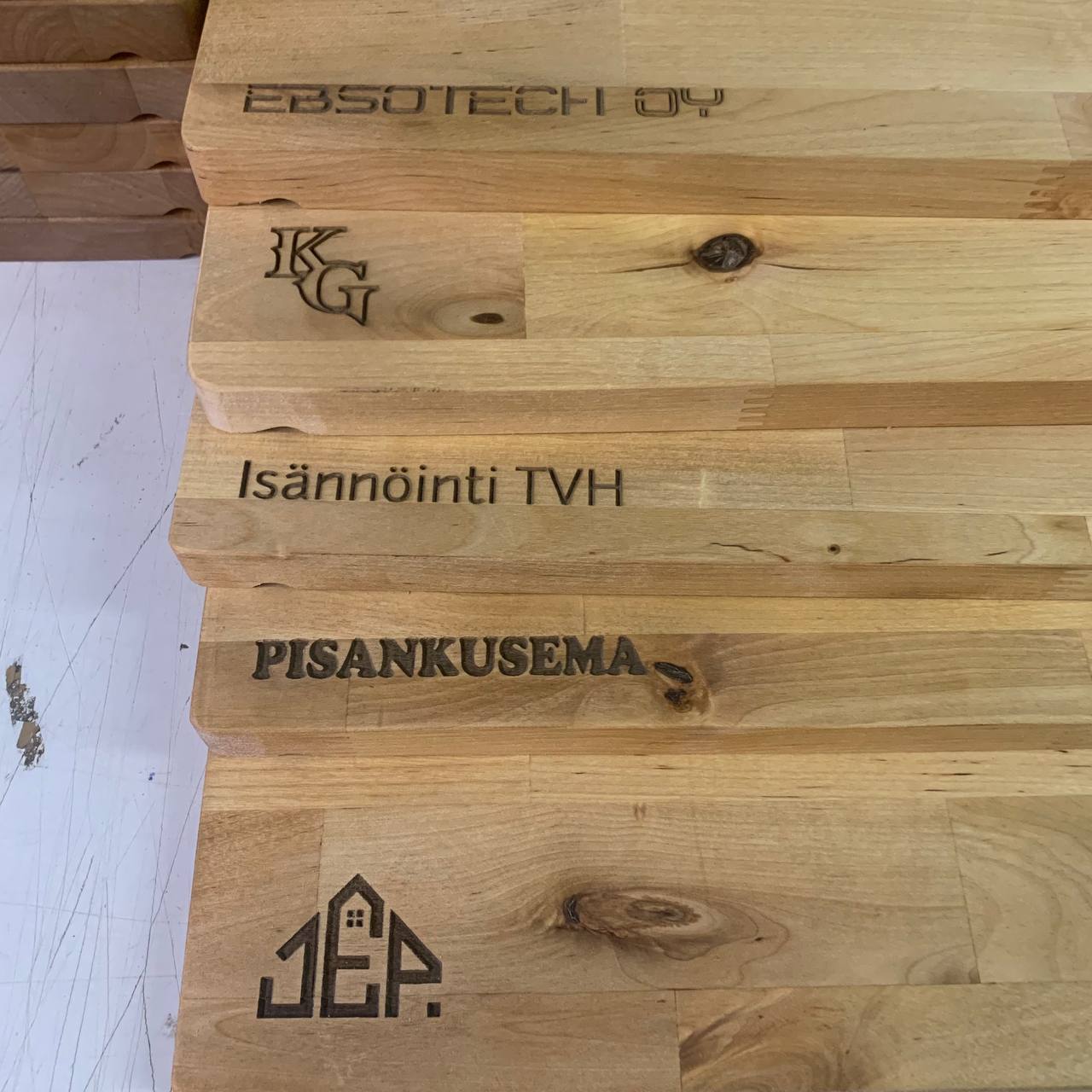 Leikkuulautojen Laserkaiverrus Lankkupojat-kumppanuudessa 4 Kasa leikkuulautoja, joissa useita erilaisia yrityslogoja laserkaiverrettuna.