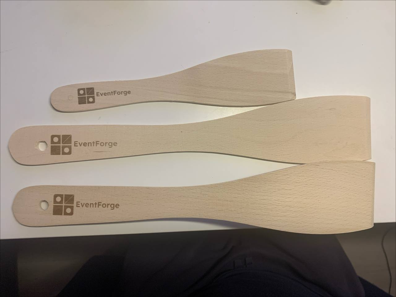 Kolme puista lastaa EventForge-logolla laserkaiverrettuna.