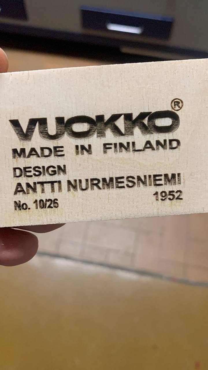Lähikuva Vuokon puiseen saunajakkaraan tehdystä syvästä laserkaiverruksesta, jossa näkyy design-tiedot ja sarjanumero.