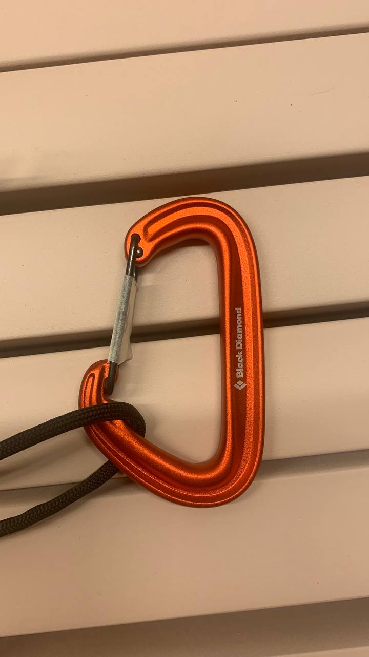 Lähikuva anodisoidusta alumiinista valmistetusta oranssista kiipeilykarabiinista.
