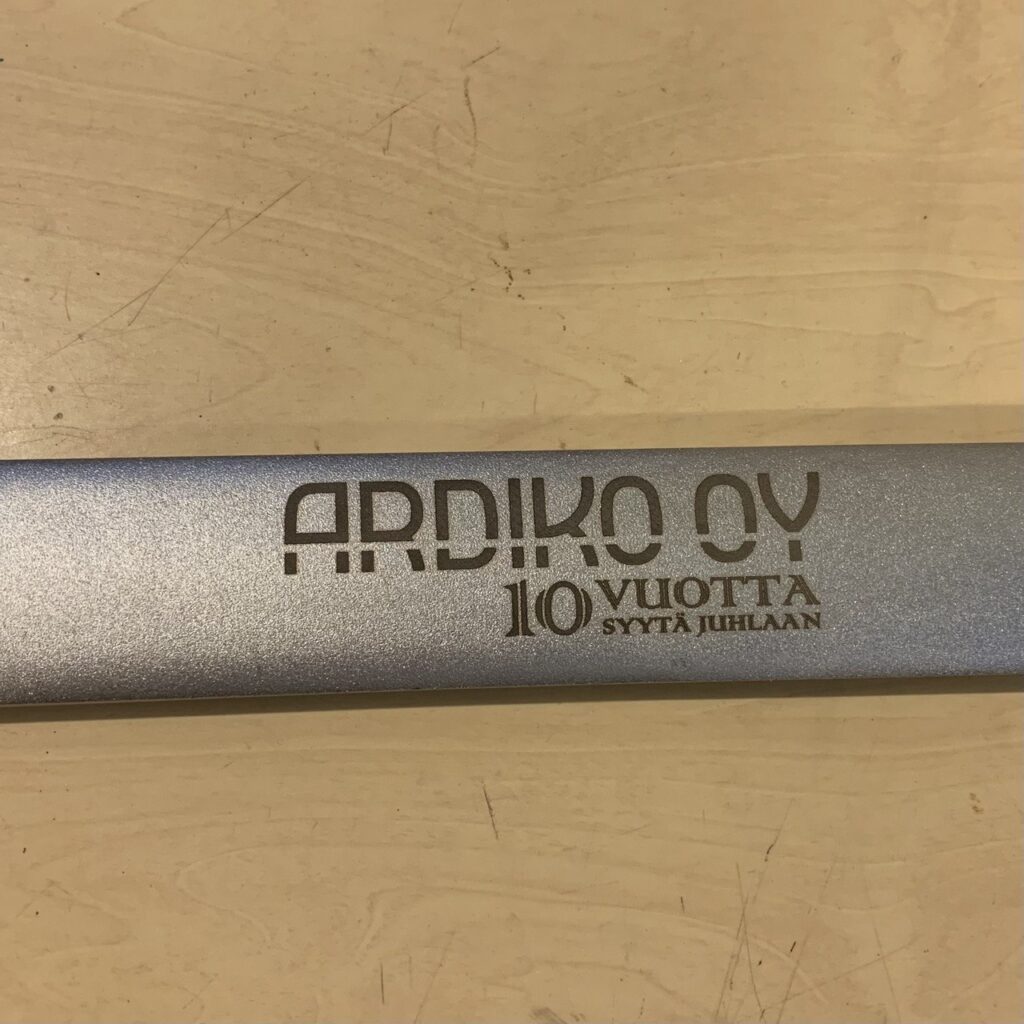 Lähikuva Ardiko OY -logolla ja "10 vuotta syytä juhlaan" -tekstillä laserkaiverretusta hopeanvärisestä kiintoavaimen kahvasta.